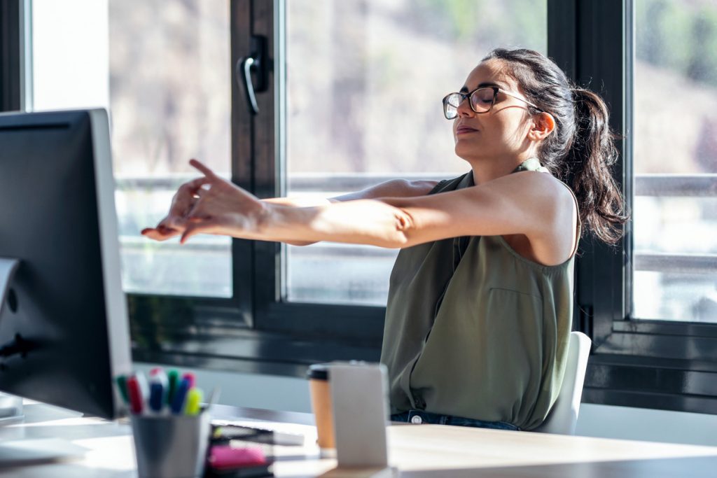 Business owner stretching after feeling content with the financial performance of her business.